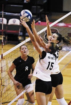 UNM's Jennifer Heasty, No. 15, and Joelle Ingram try to block a returned ball during the team's loss to Utah State on Friday at Johnson Gym. It was the first game of the Albuquerque Hilton Classic.