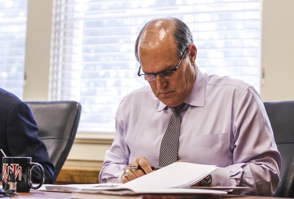 UNM President Bob Frank looks through documents from an August Board of Regents meeting. The regents, in their Tuesday meeting, covered topics such as the Department of Justice report, finding a Frank's replacement&nbsp;and the Athletics Department budget deficit.
