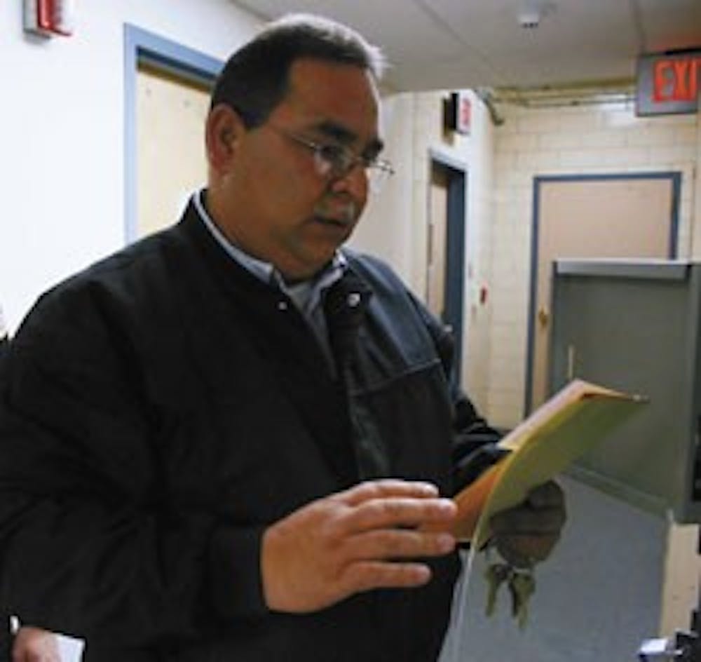 UNM Police Department evidence custodian Charles Baca removes an envelope from temporary storage before processing it into the evidence catalog Thursday at the department. 