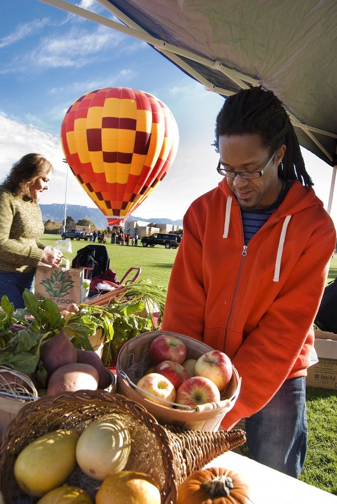 	Jason Young, Chartwells’ employee, helps set up a food service table for the Lobo Growers Market Saturday at Johnson Field. Chartwells serves local and seasonal food to dorm residents. See 5 page for the full story.