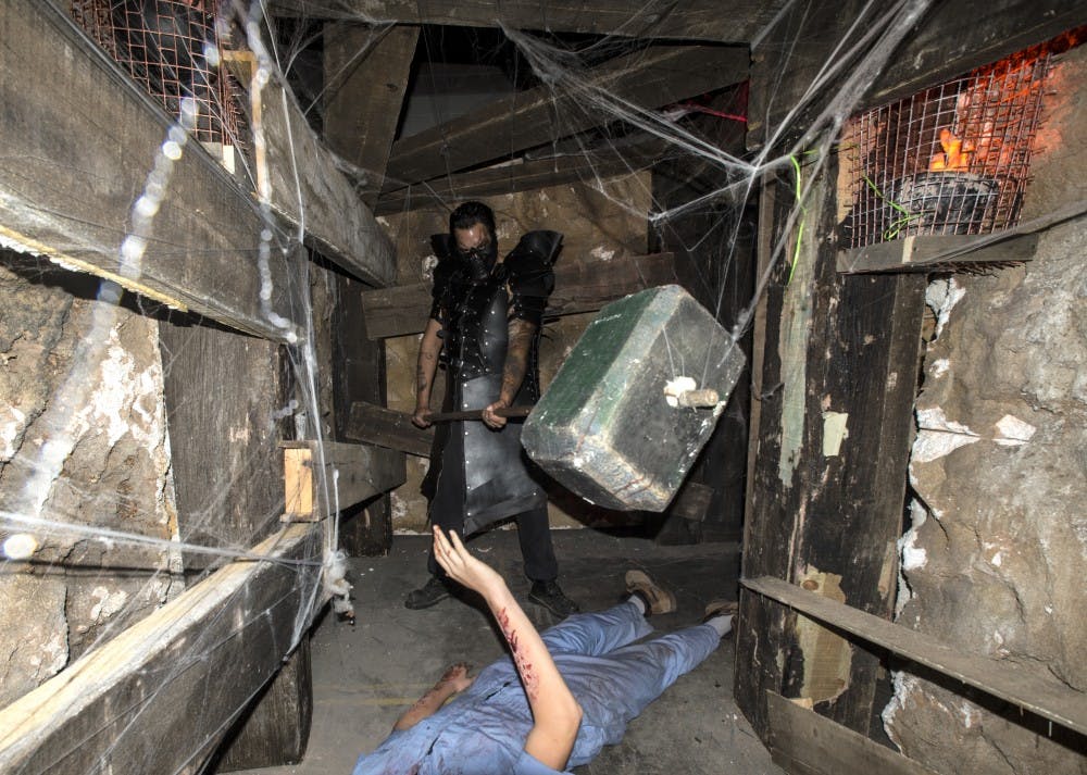 A worker at Slaughterhouse whos costume is called Leather Face, positions himself at the end of a tunnel to await the houses attendees. The Slaughterhouse is built in a warehouse that after the halloween season is over doubles as a movie production space.