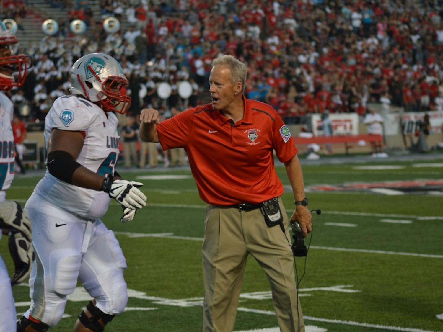 UNM Head Football Coach Bob Davie congratulates a football player after a play on Sept. 24, 2014 during a game against Fresno at University Stadium.