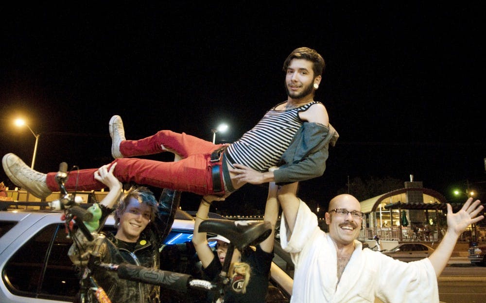 	Members of the Bike Porn crew, Larsen Farrell, left, Courtney Rodgers, center, and Reverend Phil, hold up Joshua Staley in front of the Guild Cinema on Sunday night. Bike Porn was featured in Self Serve’s Pornotopia festival at the Guild this weekend. Bike Porn is accepting independent films for their fourth project “Bike Porn 4 Play.”