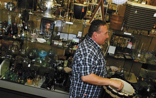 Michael Gonzales carries a lamp through the aisles on the second floor of the Classic Century Square on Central Avenue on Tuesday. Gonzales has been a vendor at the second floor flea market for two years.
