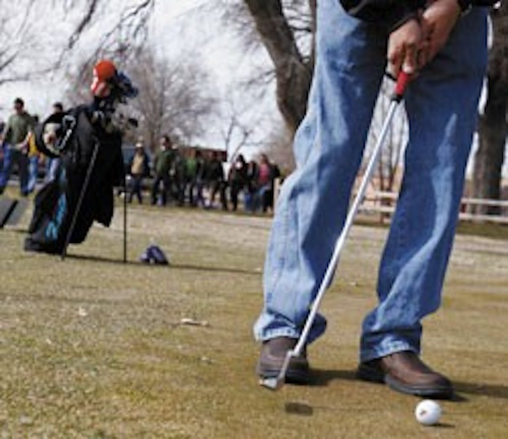 Golfer Pete Sierra practices his stroke before a putt at the UNM North Golf Course on Sunday. About 700 people rallied to protest its possible development.