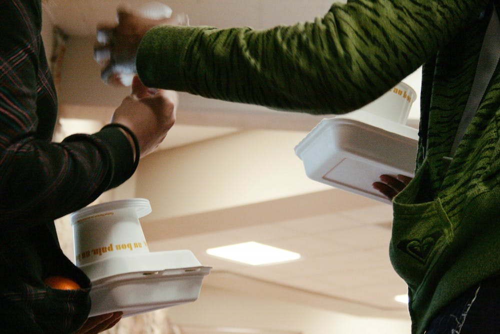 	Students Jasmine McDonald, right, and Jennifer Vaca gather their paper and plastic to-go containers in La Posada Dining Hall on Monday. Students tossed out thousands of disposable utensils and plates couldn’t be used due to pending inspection.