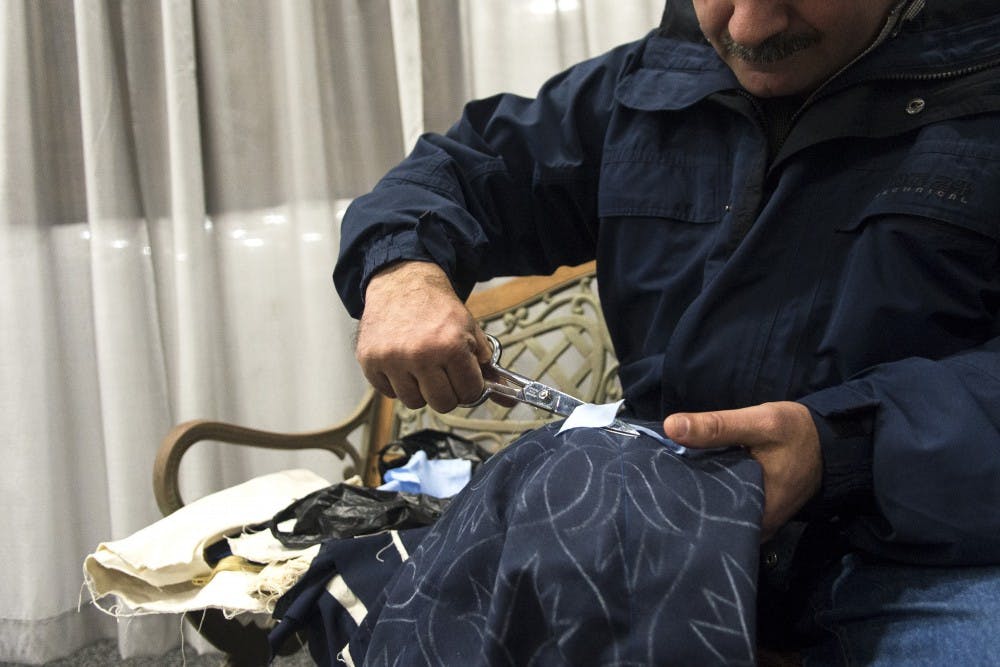 Tarek Abdelhay sews a leaf onto an unfinished panel.