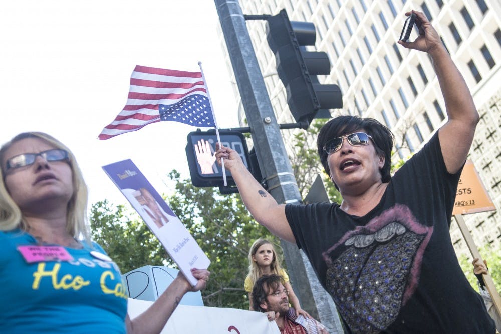 	Dinah Vargas shouts to fellow protesters that she has been trying to get Albuquerque Mayor Richard Berry’s office on the phone June 9. Vargas, along with 50 other protesters, met in front of Albuquerque City Hall before the start of the City Council meeting last week.