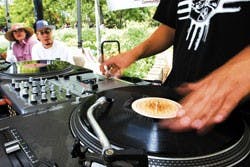 Sylas Marchiondo, aka DJ Scientific, plays music at the KUNM tent near the Duck Pond on Wednesday. KUNM Operations Manager Rachel Kaub and Bruce Chavez, aka DJ Intreeg, listen to Marchiondo, who also hosts the KUNM program "Street Beat" on Friday nights.