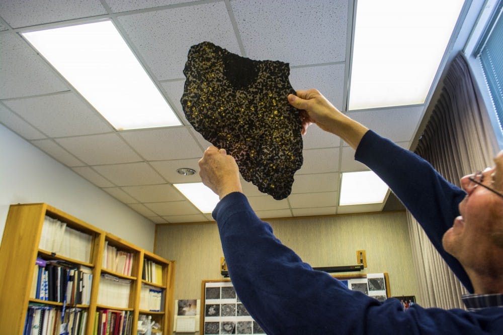 Carl Agee holds up a meteorite from the collection at Northrop Hall. Agee is currently working on updating the Meteorite Museum for an April opening.