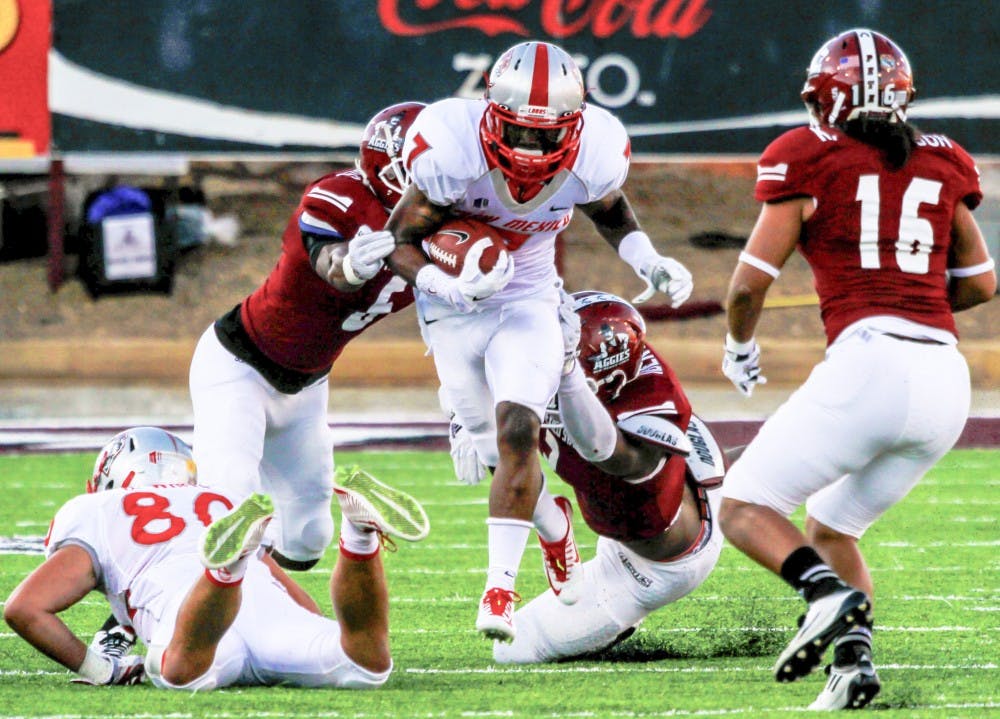 UNM running back Teriyon Gipson (7) runs through the middle of the NMSU defense during the Rio Grande Rivalry game Saturday night at Aggie Memorial Stadium in Las Cruces. The Lobos gained their first win of the season against the Aggies 38-35.