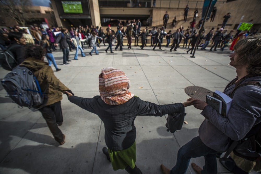 A large circle of demonstrators holds hands and revolves together as part of an anti-Trump walkout on Friday, Jan. 20, 2016 on UNM Main Campus. Community members and students stood at a podium and voiced their opposition to the official start of&nbsp;President Donald Trump's administration.&nbsp;