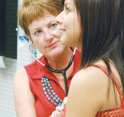 Dr. Nancy McGough examines student Kimberly Pereyra Saturday at Student Health and Counseling. Students eligible for UNM's insurance plans must enroll by Sept. 15. 