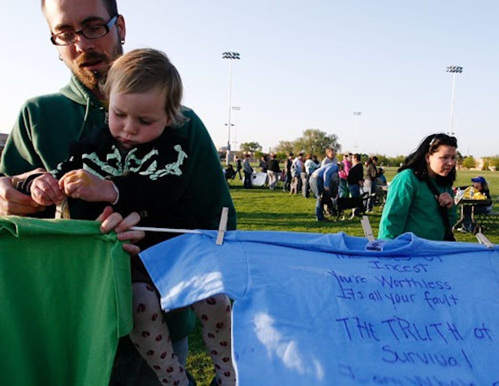 Joshua Clair holds his daughter, Isabella LaClair Crowe-Dexter, during Take Back the Night at Johnson Field on Friday.  