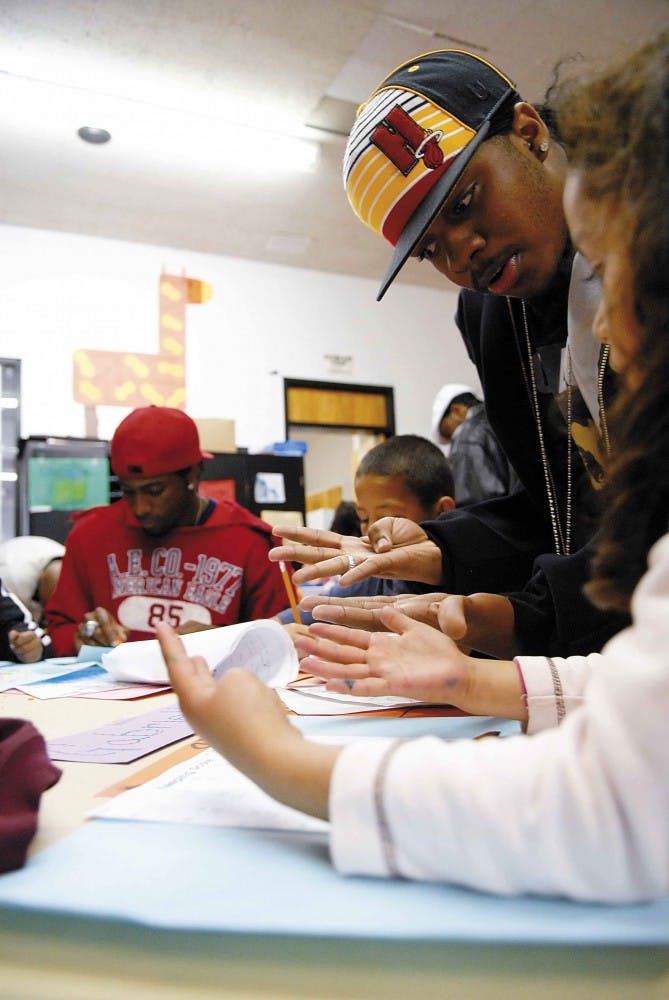 Student and member of Black Men in Motion Cameron Cuttler helps a 5-year-old girl with homework at the Thomas Bell Comm-unity Center on Tuesday.