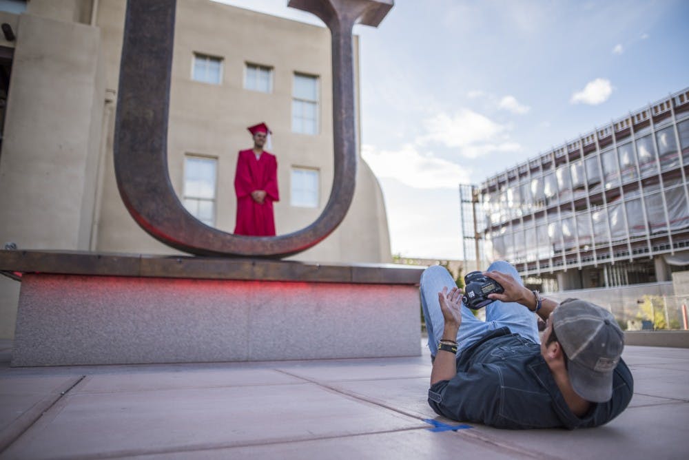 Ryan Montano lays on the ground to get a different point of view of an upcoming UNM graduate.