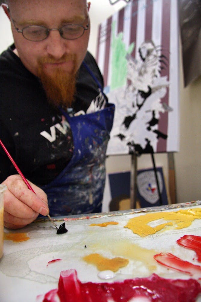 	Louis Herring makes an addition to one of his pieces depicting the American flag, the Statue of Liberty and Predator in the Art Building on Tuesday.