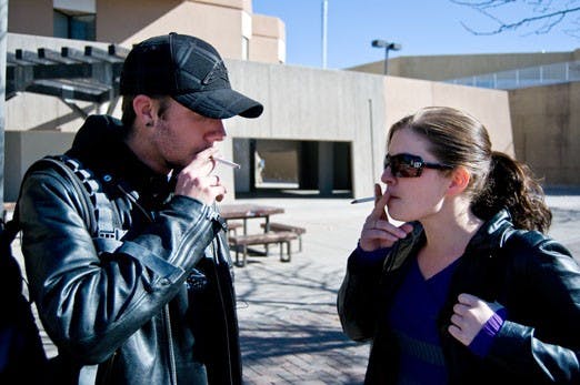 Justin Cumley and Samantha Brooks smoke outside Ortega Hall on Thursday. UNM plans to ban smoking on campus in August. 