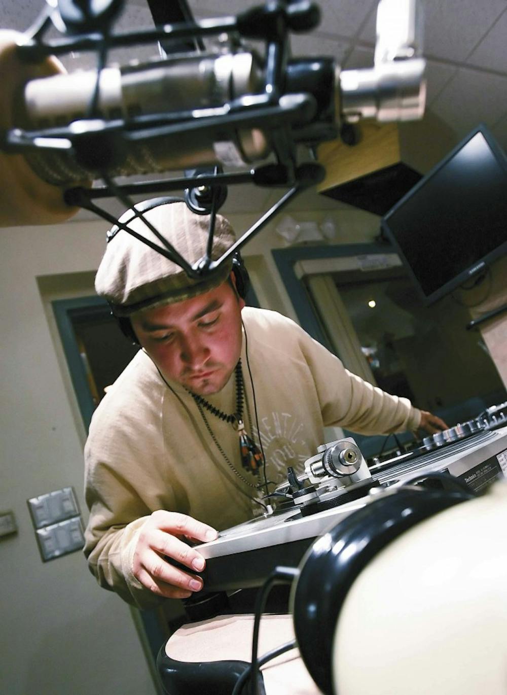 Leon "DJ Badger" Archuleta puts an album on a record player during the hip-hop radio show "Street Beat" at the KUNM studios in O