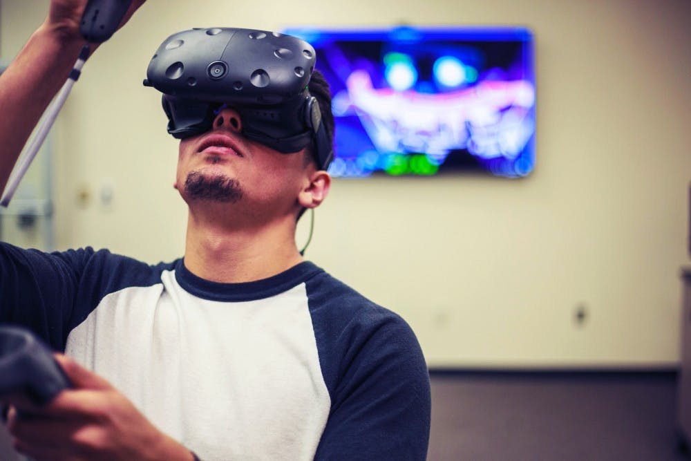 Derek Luna, library technical assistant and junior civil engineering major at UNM, plays a game on the new VR system inside Centennial Library. Luna says that, aside for gaming purposes, he plans to use VR to view his architectural designs.
