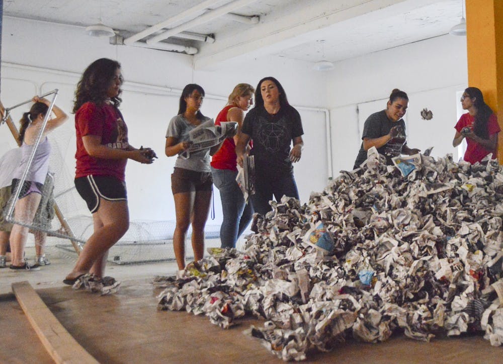 	Members of the Associated Students of the University of New Mexico and other UNM students crumple up issues of newspapers in the basement of Sigma Chi House on Tuesday afternoon to build an effigy of the New Mexico State University Aggie. The Aggie effigy will be burned during Red Rally at Johnson Field on Sept. 18 at 8 p.m.