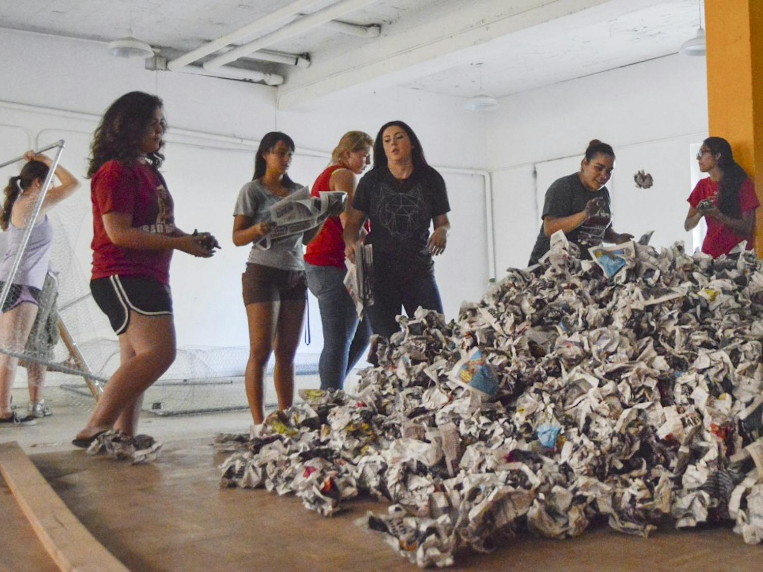 Members of the Associated Students of the University of New Mexico and other UNM students crumple up issues of newspapers in the basement of Sigma Chi House on Tuesday afternoon to build an effigy of the New Mexico State University Aggie. The Aggie effigy will be burned during Red Rally at Johnson Field on Sept. 18 at 8 p.m.
