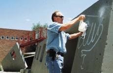 UNM maintenance worker Mark Earns removes graffiti at the School of Architecture and Planning on Wednesday.