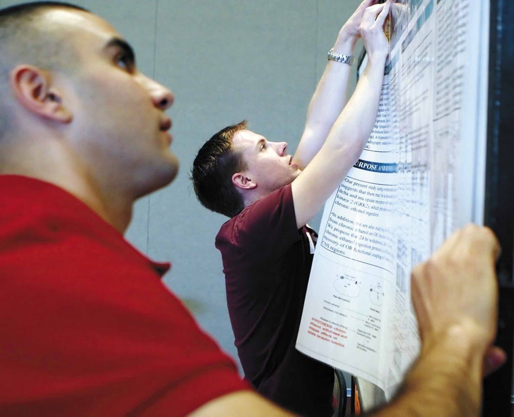 Students David Lee, right, and Rafael Garcia set up during the Undergraduate Research and Creativity Conference in the SUB on Monday.