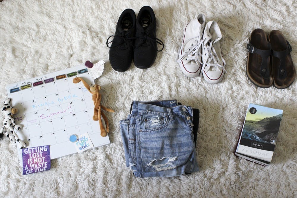 Essential items to pack lay on the floor in a student's dorm, including: a calendar, jeans, shoes and favorite books.