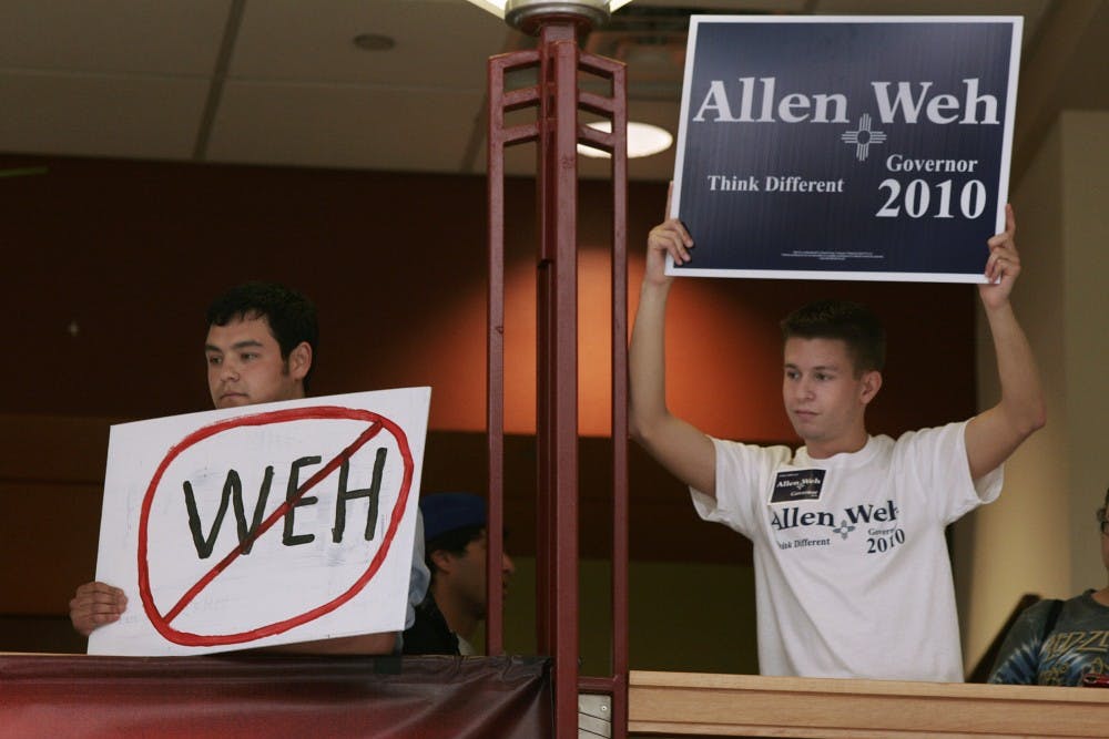 	Students Ruben Pancheco, left, and College Republicans Vice President Eric Mcinteer, hold signs during Weh’s announcement in the SUB Atrium on Tuesday. Pancheco and a handful of others said Weh’s history has shown otherwise.