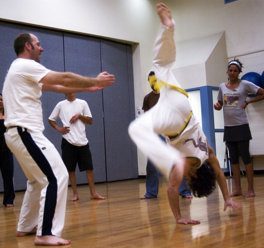 	Greg Suchocki, left, helps student Sean O’Brien practice a capoeira kick on March 1 in Johnson Gym. The capoeira club meets every Monday and Wednesday starting at 8 p.m.