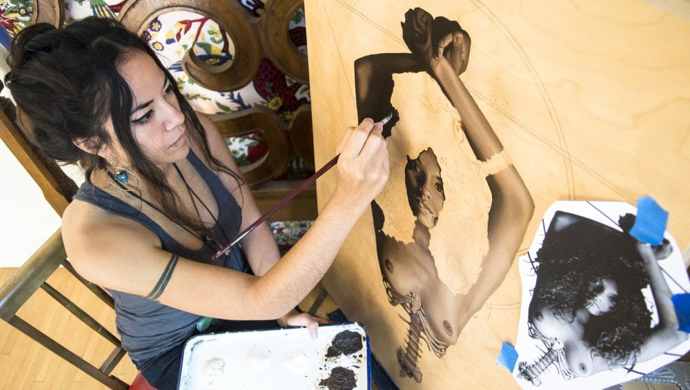 Jodie Herrera works on an oil art piece for her solo art show titled “The Shape I’m In” on Thursday. Herrera combined her show with a raffle of works by local artists to benefit Albuquerque Healthcare for the Homeless. The show will be held Nov. 22 at Tractor Brewery.