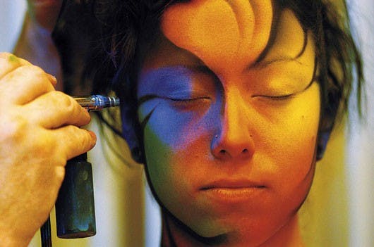 Pashur House paints Sharon Mae with an airbrush during the New Mexico Body Painting Festival on Sunday at the Embassy Suites by Lomas Boulevard and I-25.