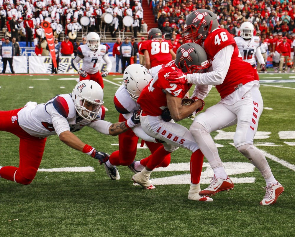Senior wide receiver Carlos Wiggins (24) is brought down down by Arizona's defense at University Stadium Saturday afternoon. The Lobos lost to the Wild Cats 45-37 in the 10th Gildan New Mexico Bowl.&nbsp;