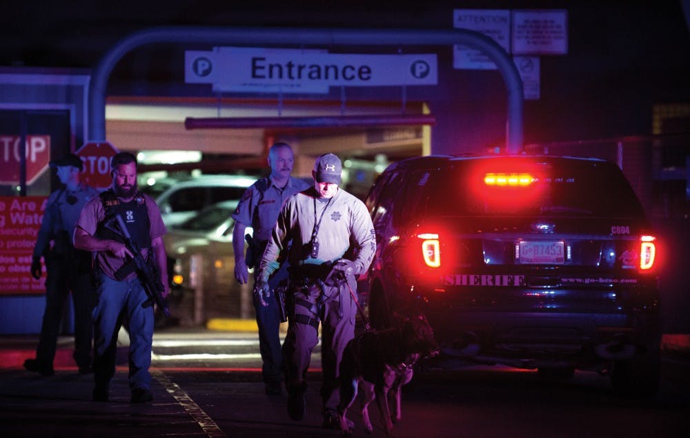 Police officers exit the UNMH parking structure Thursday night after searching all of its floors. Officers were looking for two suspects who previously evaded APD with a stolen vehicle and hid into the structure.