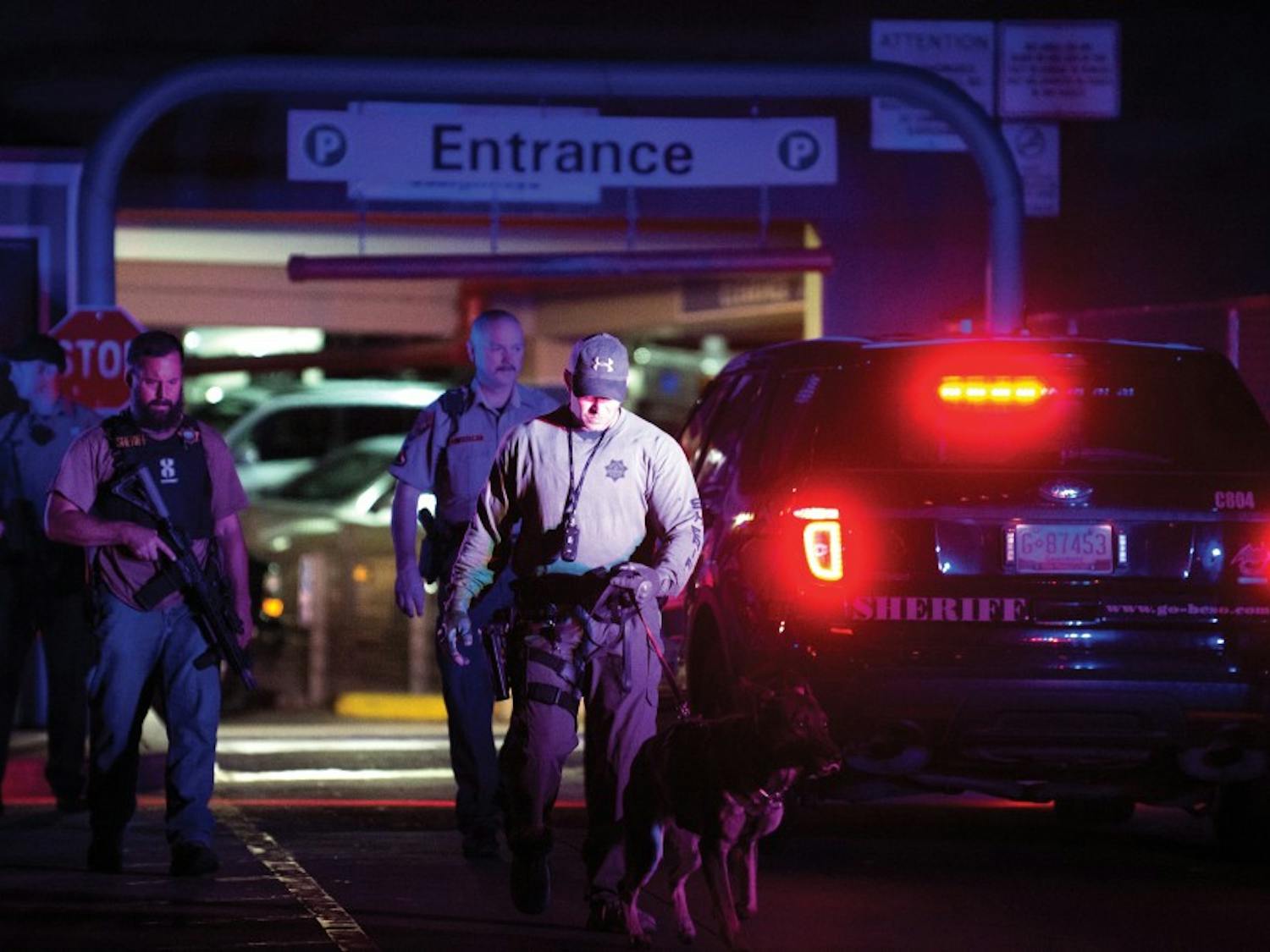 Police officers exit the UNMH parking structure Thursday night after searching all of its floors. Officers were looking for two suspects who previously evaded APD with a stolen vehicle and hid into the structure.