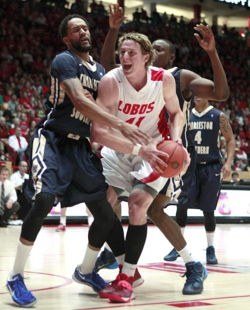 UNM forward Cameron Bairstow tries for two and is fouled down by Charleston's Will Saunders #1 and Alhaji Fullah #35 Sunday night at the Pit. UNM won the game against Charleston 109-93.