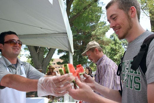 Victor Chacon hands watermelon to Peter Ver Brugger on Tuesday during Welcome Back Days near the Duck Pond. 