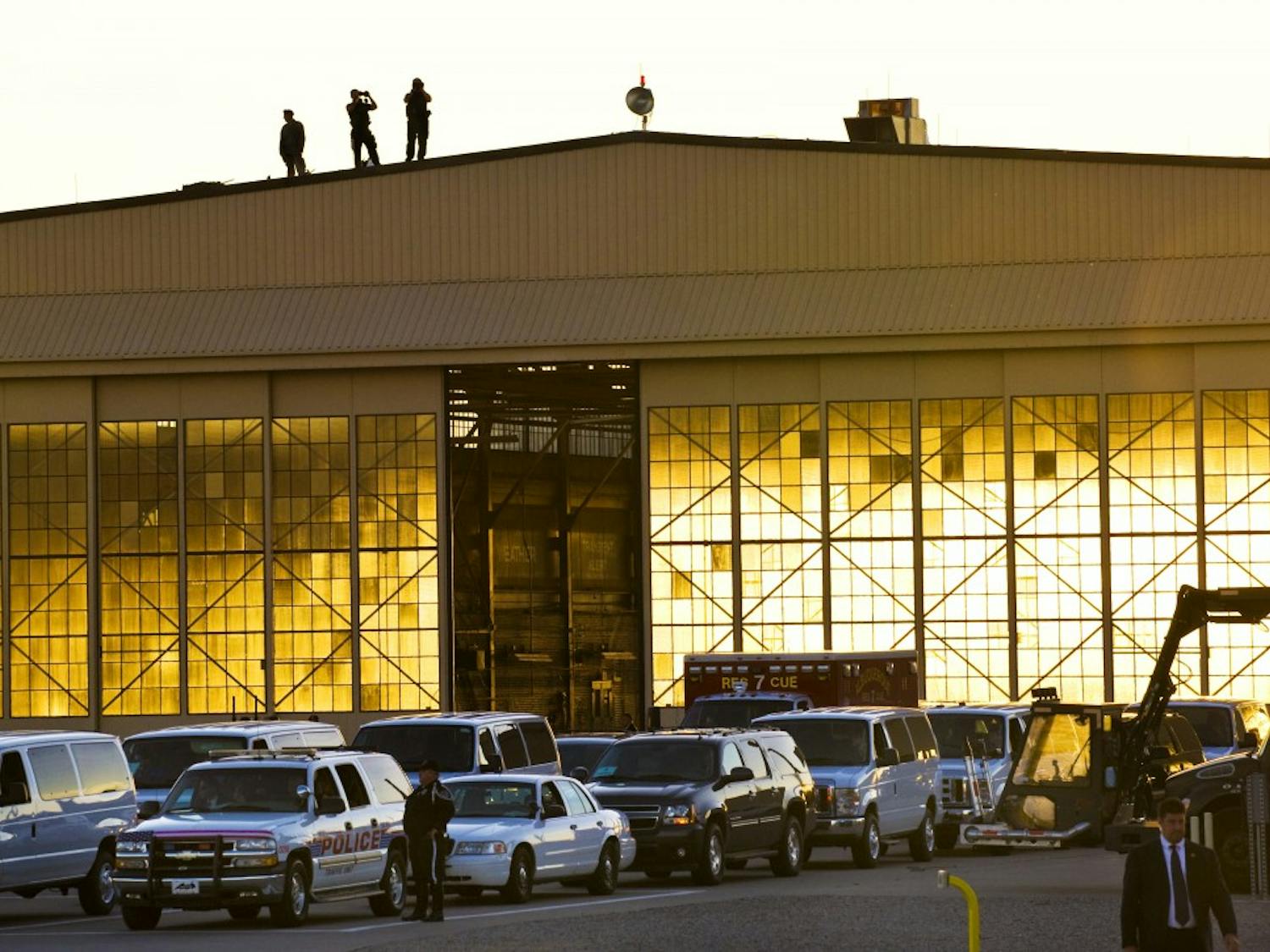 	Security officials monitor the Air Force One landing site atop a hangar before President Obama’s arrival. 