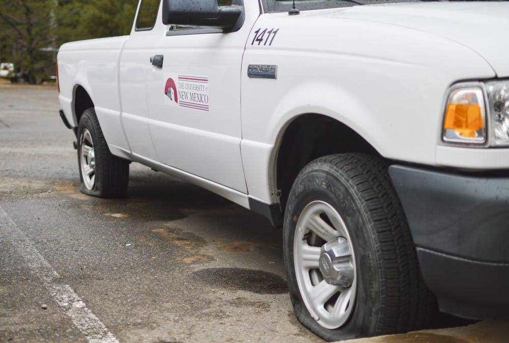 A UNM truck with two flat tires sits parked west of Marron Hall on Sunday afternoon.