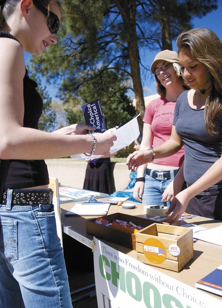 Volunteers Samantha Luna, right, and Melissa Long, center, give information about contraception to student Vanessa Baechtel in Smith Plaza on Tuesday. The event was sponsored by NARAL Pro-Choice New Mexico to help raise awareness about contraceptive optio