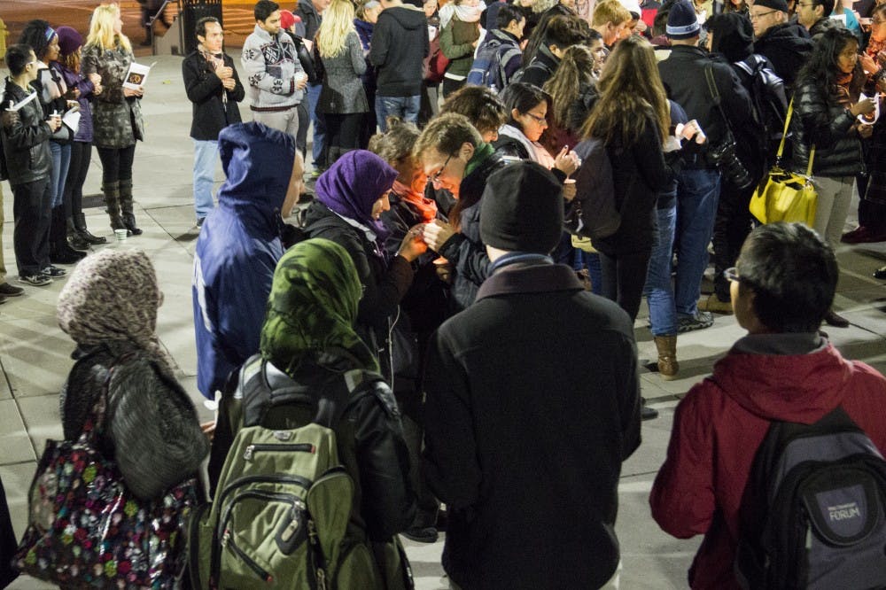 People gather in front of the Book Store Wednesday night in the remembrance of the lives lost in the Paris attacks that took place Nov. 13. At the vigil the French national anthem was played alongside speeches and a moment of silence.