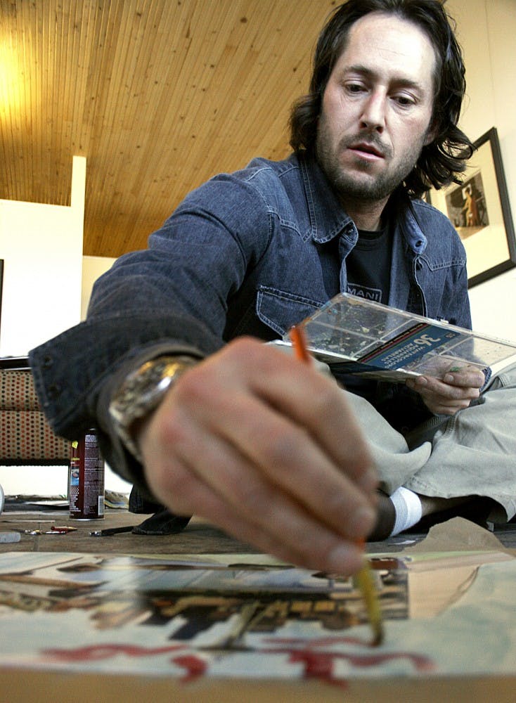 Artist Wain Wayne finishes a collage Saturday at his studio.