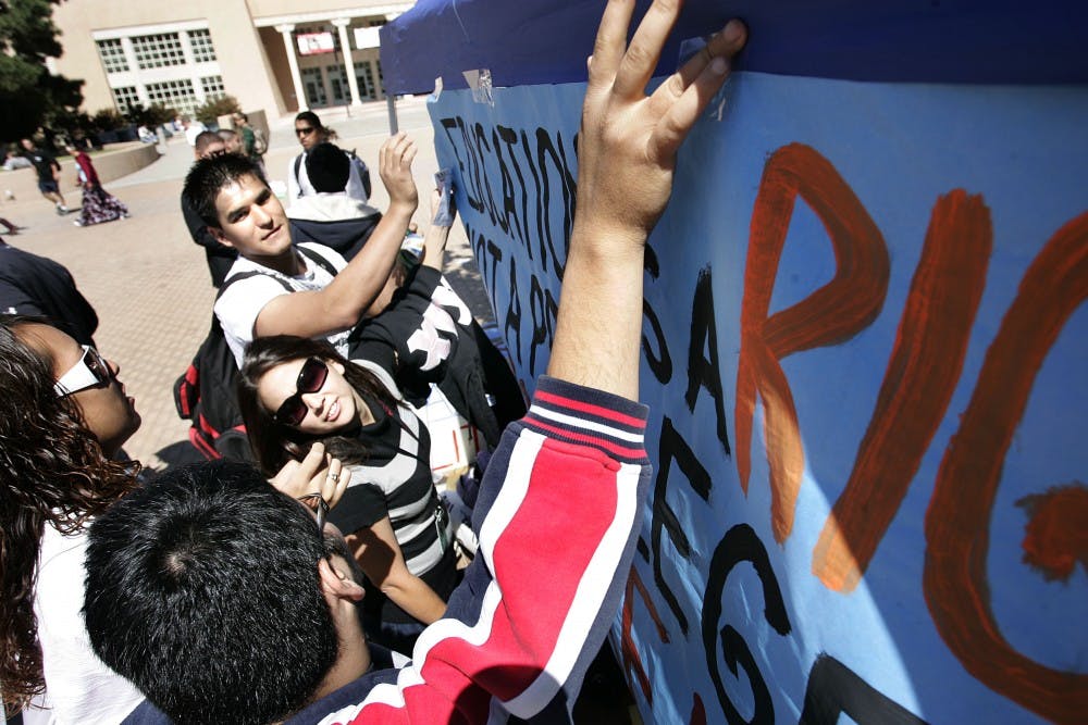 	Students hang a sign supporting the DREAM Act at Smith Plaza on Wednesday. The DREAM Act aims to give undocumented high school graduates a chance at higher education, as long as they don’t have criminal records. 