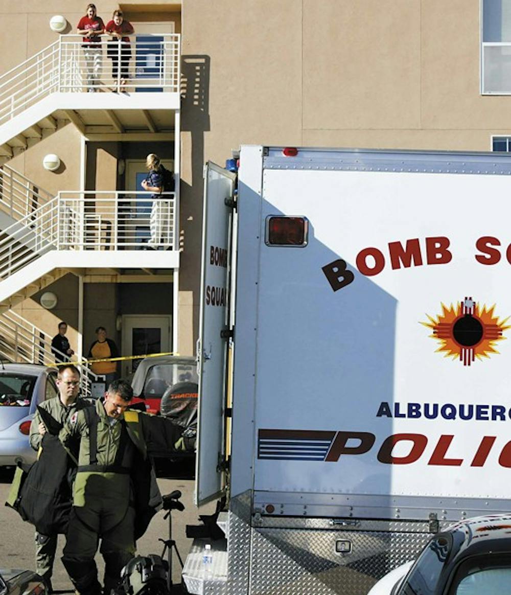 The Albuquerque Police Department's bomb squad technicians finish investigating two suspicious packages Monday, while residents of Redondo Village Apartments watch from a stairwell. 