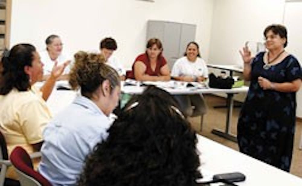 Annemarie Werner-Smith, right, one of the teachers of the new English Literacy Program for UNM Employees, works with Maria Rodriguez, far left, to translate a word during class Tuesday at the UNM Business Center.