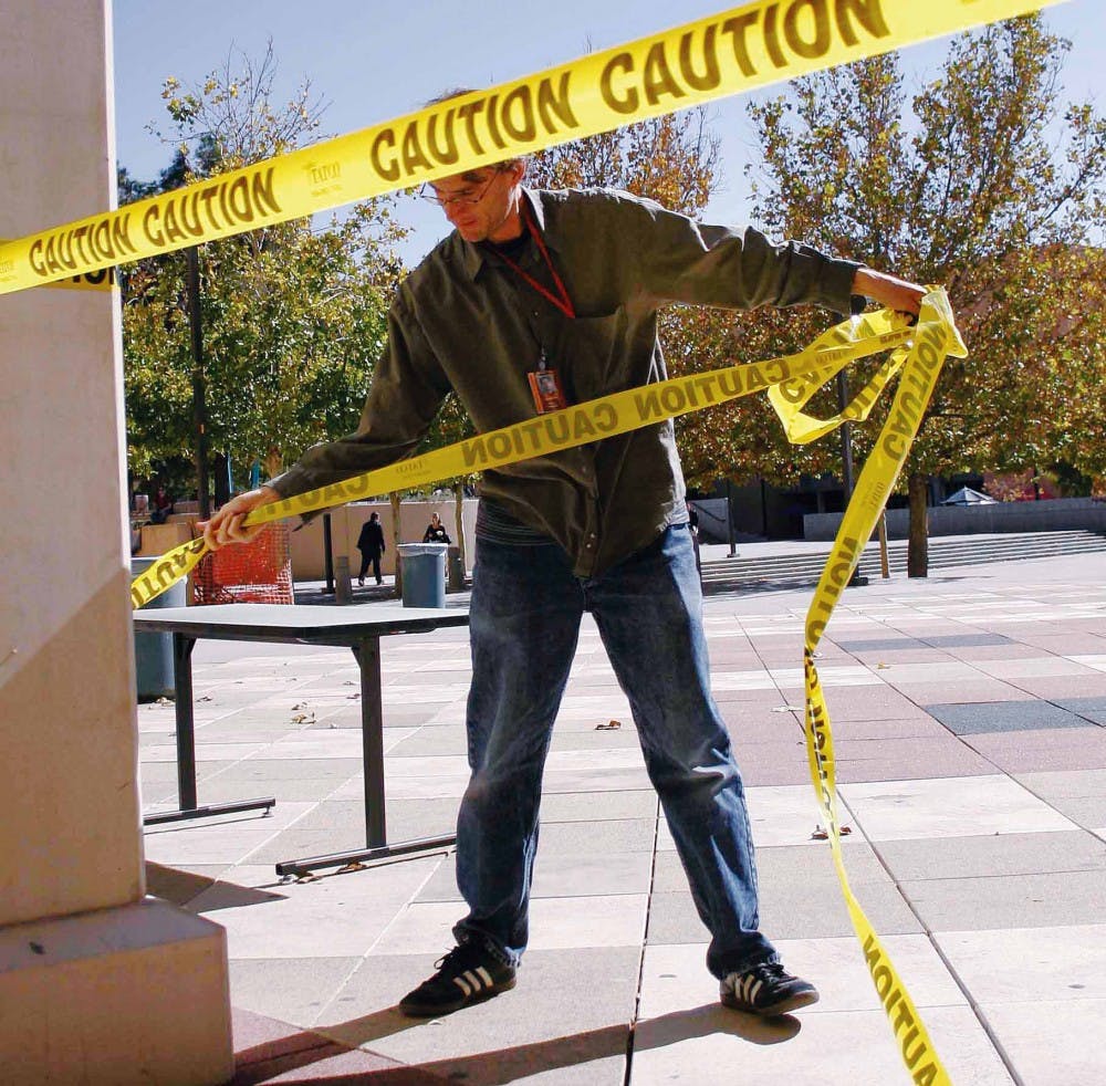 Zimmerman Library technician Aaron Blecha takes down caution tape in front of the library's entrance on Thursday. The library reopened Thursday after a pipe burst and flooded the basement on Wednesday.   