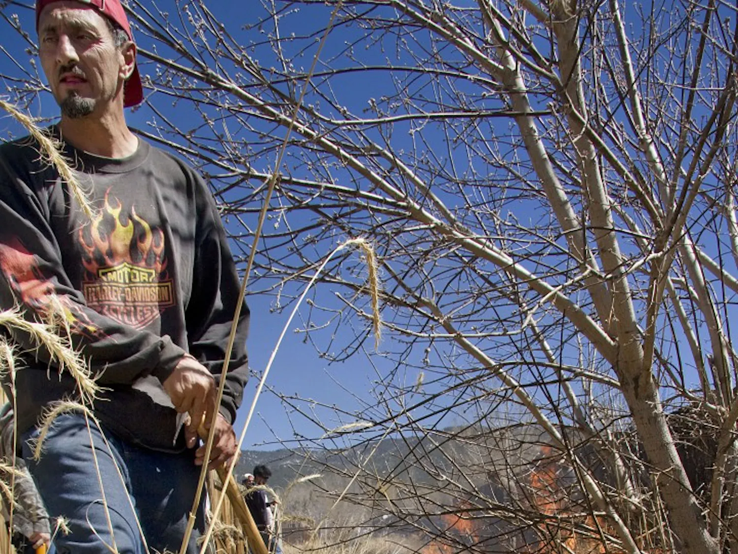 Gustavo Lucero drags a rake with burning brush through the acequia to help clear it out before they run the water. Santistevan said the acequia runs for one week to recharge the groundwater supply before they
distribute it to acequia members.