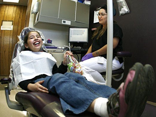 Fourth grader Maria Pineiro smiles after receiving a toothbrush and floss from dental assistant Elizabeth Marie Duran on Friday at Dr. Charles Tatlock's dental clinic. Pineiro was one of 20 children to get free dental care for Give Kids a Smile day.