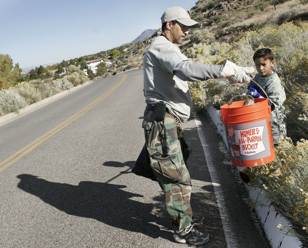 	Anthony Freitas and his son, Artemas, clean up trash at Piedra Lisa Open Space Area Saturday morning. The father-son team participated in volunteering as part of national Make a Difference Day. 